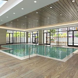 A modern indoor swimming pool with wooden flooring and large glass windows.