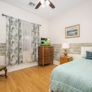 A cozy bedroom with a bed, dresser, and a small aquarium under soft lighting.
