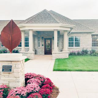A well-maintained building entrance with a sculpture and landscaped garden.