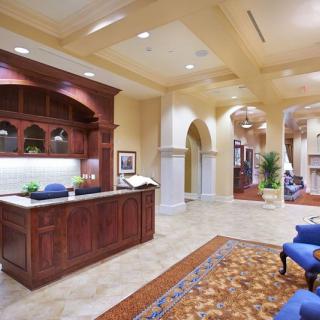 A spacious and elegantly designed office reception area with a wooden desk, comfortable seating, and decorative elements.