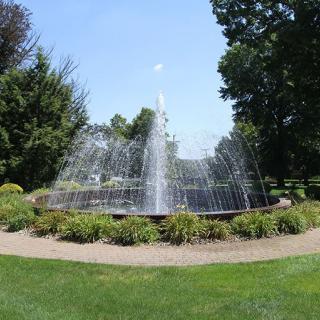 A scenic fountain surrounded by greenery in a tranquil garden setting.