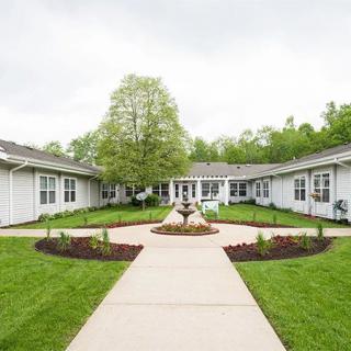 A serene courtyard with a central pathway surrounded by greenery and a building.