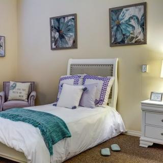 A cozy bedroom with a single bed, nightstand, and decorative artwork on the walls.