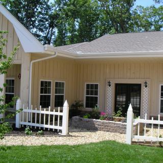A charming residential house with a white fence and green lawn.