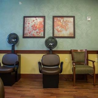 A cozy waiting area in a salon featuring comfortable chairs and decorative artwork.