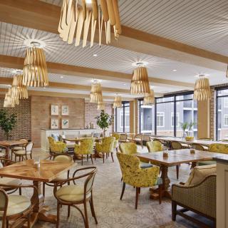 A modern restaurant interior featuring wooden decor, comfortable seating, and stylish chandeliers.