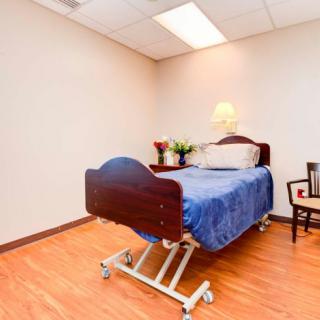 A hospital room with a single bed and a chair, featuring simple decor.