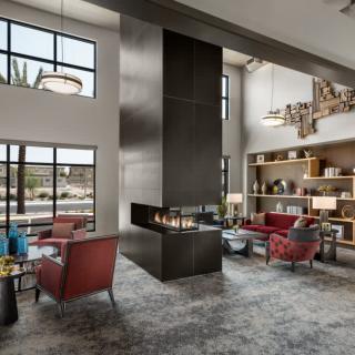A modern living room with a central fireplace and large windows.