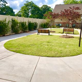 A well-maintained garden with a circular pathway, benches, and lush trees.