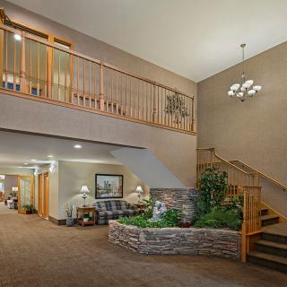 Spacious lobby interior with a staircase, seating area, and decorative plants.