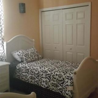 A bedroom with a single bed featuring patterned bedding and a closet with sliding doors.