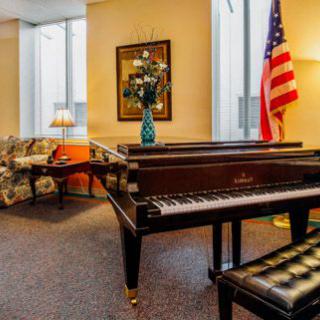 A cozy room featuring a grand piano, an American flag, and comfortable seating arrangements.