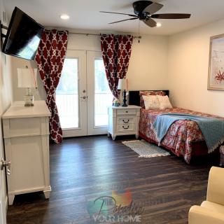 A cozy bedroom with a single bed, decorated with red patterned curtains and a wall-mounted TV.