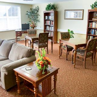 A cozy living room with a sofa, tables, chairs, and bookshelves.