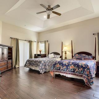 A spacious bedroom with two beds, wooden flooring, and a ceiling fan.