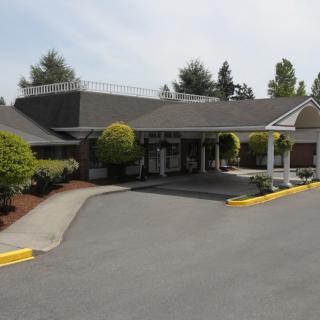 A suburban building with a landscaped entrance surrounded by trees and bushes.