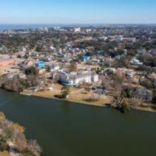 Aerial view of a cityscape featuring a river and residential buildings surrounded by trees.