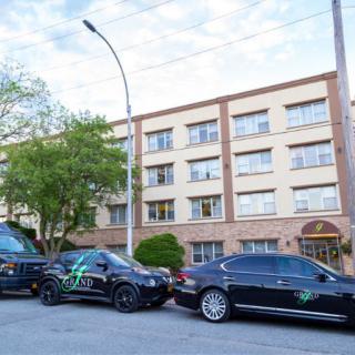 A row of black sedans parked on a city street in front of a multi-story building.
