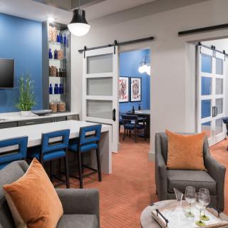 A modern lounge area with blue walls, offering cozy seating and a workspace with bar stools.