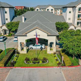 Aerial view of a residential complex entrance with landscaped gardens and a flag displayed.
