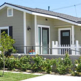 A cozy bungalow with a small garden and a white picket fence.