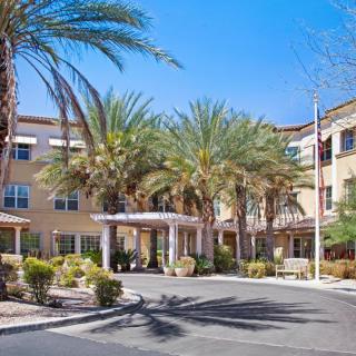 A residential building with a landscaped entrance and palm trees.
