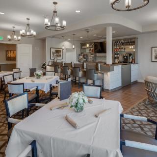 Elegant restaurant dining room with neatly arranged tables and a bar area.