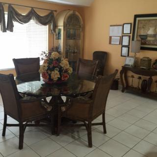 A well-decorated dining room featuring a round table with chairs and a floral centerpiece.