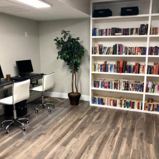 A modern office space with computers and a bookshelf filled with books.