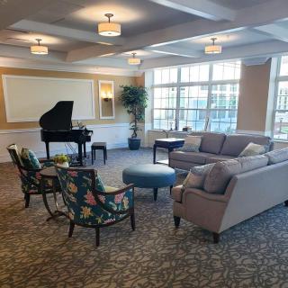 A cozy living room with a grand piano, comfortable seating, and large windows.