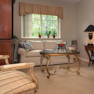 A cozy living room with a sofa, elegant coffee table, and large window with plants.