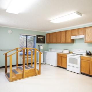 A spacious kitchen featuring wooden cabinets, essential appliances, and a wheelchair-accessible ramp.