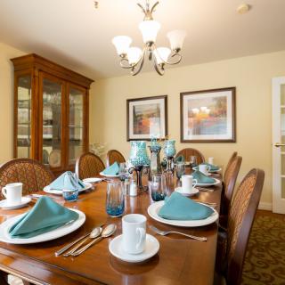A well-arranged dining room with a wooden table set for a meal, featuring elegant decor and ambient lighting.