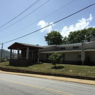 A building with a sloped roof located along a street under a clear sky.