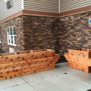 Wooden planters placed against a brick wall on a sidewalk.