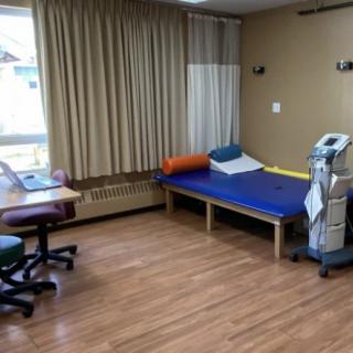 A hospital room with a bed, medical equipment, and a wooden floor.