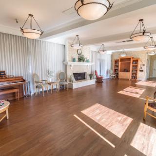 A spacious and inviting community lounge, featuring elegant chandeliers and warm wooden flooring.