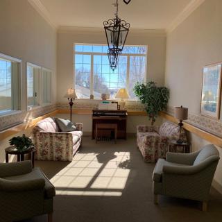 A cozy sunlit seating area with comfortable chairs and a piano.
