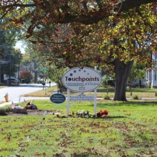 A sign surrounded by trees and grass on a sunny autumn day.