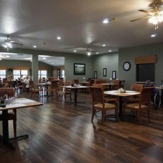 A spacious restaurant dining area with wooden floors and neatly arranged tables and chairs.