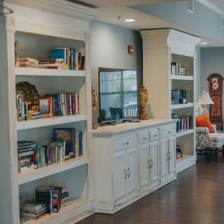 A cozy living space with a large white built-in bookshelf filled with various books and decorative items.