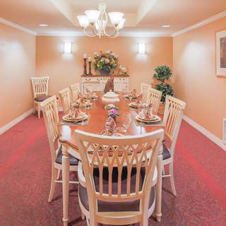 A warmly lit dining room with a long table and elegant chairs.