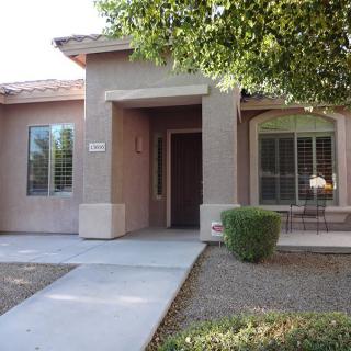 Front view of a residential house with a pathway and small shrubs.