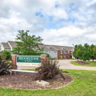 Entrance of a residential apartment complex with landscaped surroundings and clear skies.