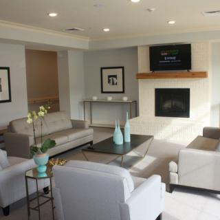 A modern living room with comfortable seating, a TV above a fireplace, and stylish decor.