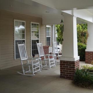 A cozy front porch with white rocking chairs and brick accents.
