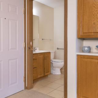 View of a bathroom featuring a toilet, sink with a mirror, and wooden cabinets.