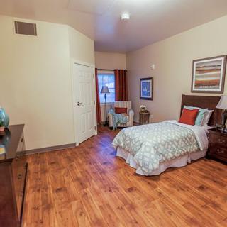A cozy bedroom with a single bed and wooden flooring, featuring simple yet elegant decor.