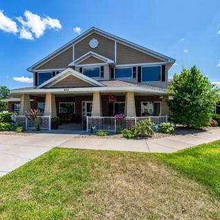 A modern two-story residential house with landscaped front yard under a bright blue sky.