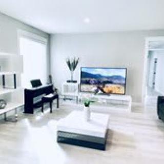 A bright, modern living room with minimalist decor and a large television.